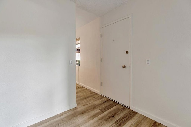 hallway featuring light hardwood / wood-style flooring and a textured ceiling