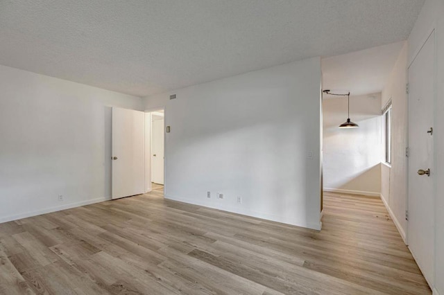 unfurnished room with a textured ceiling and light wood-type flooring