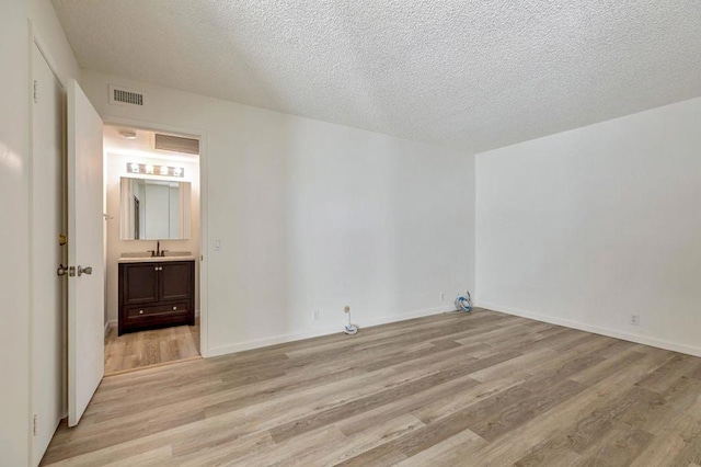 interior space featuring sink, a textured ceiling, and light wood-type flooring