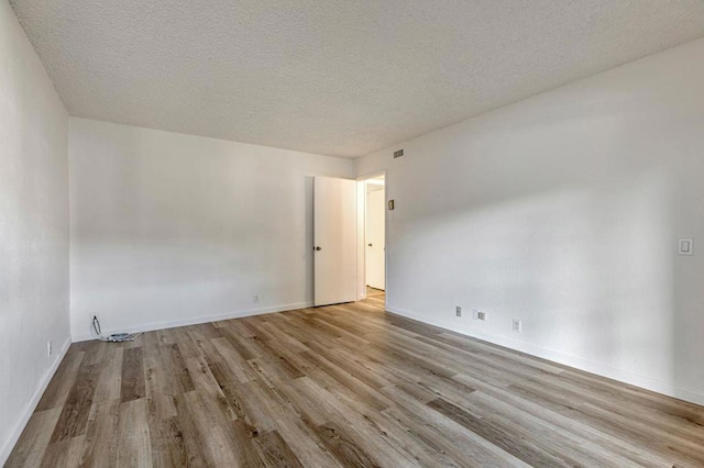 empty room with light hardwood / wood-style floors and a textured ceiling