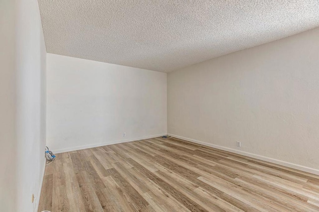 empty room with light hardwood / wood-style floors and a textured ceiling