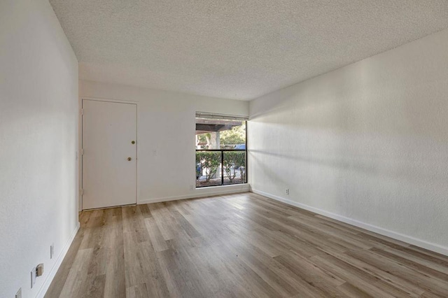 spare room featuring a textured ceiling and light hardwood / wood-style floors