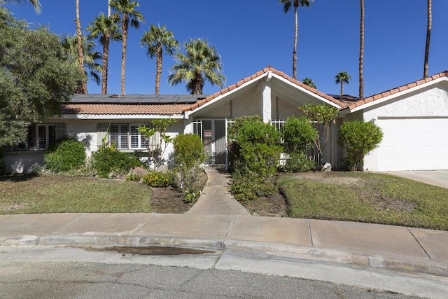 view of front of home with a garage, a front lawn, and solar panels