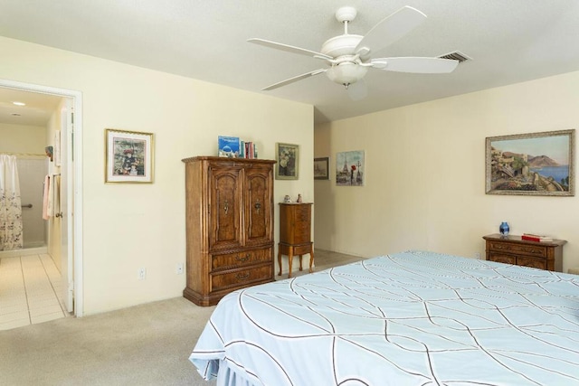 bedroom featuring light carpet, ensuite bath, and ceiling fan