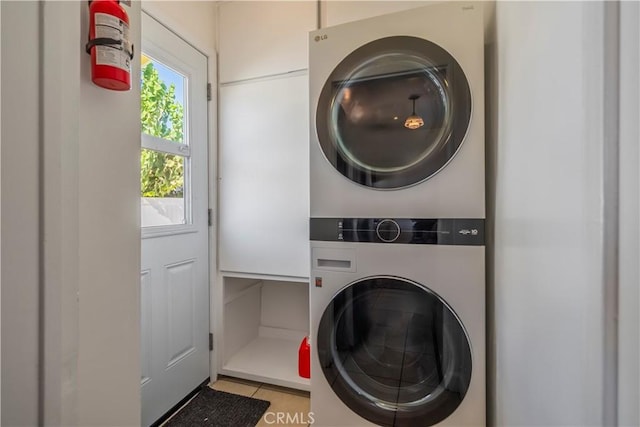 laundry room featuring light tile patterned floors and stacked washer and clothes dryer