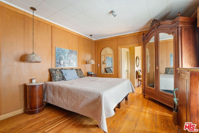 bedroom featuring hardwood / wood-style floors, crown molding, and wooden walls