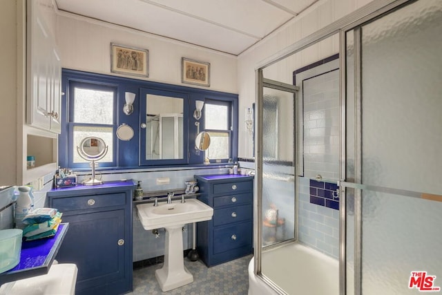 bathroom featuring plenty of natural light, combined bath / shower with glass door, and tile walls