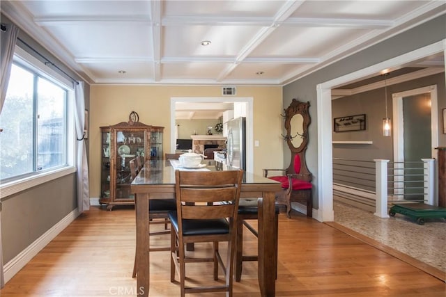 dining space with crown molding, beamed ceiling, light hardwood / wood-style floors, and coffered ceiling