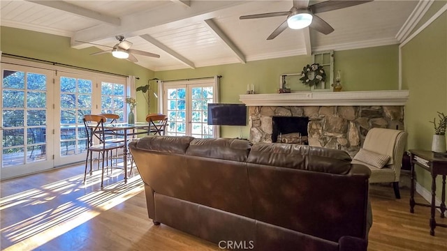 living room featuring vaulted ceiling with beams, ceiling fan, a fireplace, and wood-type flooring