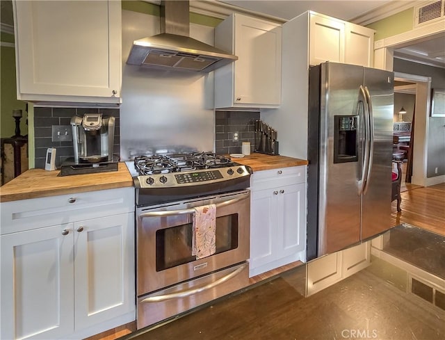 kitchen featuring backsplash, wooden counters, white cabinets, wall chimney exhaust hood, and stainless steel appliances