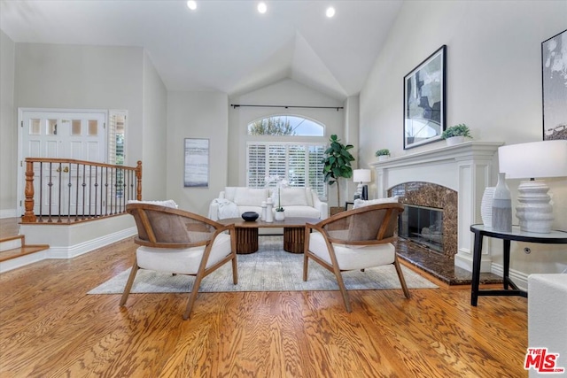 sitting room featuring a fireplace, lofted ceiling, and light wood-type flooring