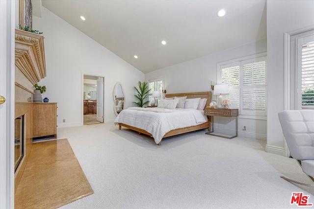 carpeted bedroom with high vaulted ceiling and connected bathroom