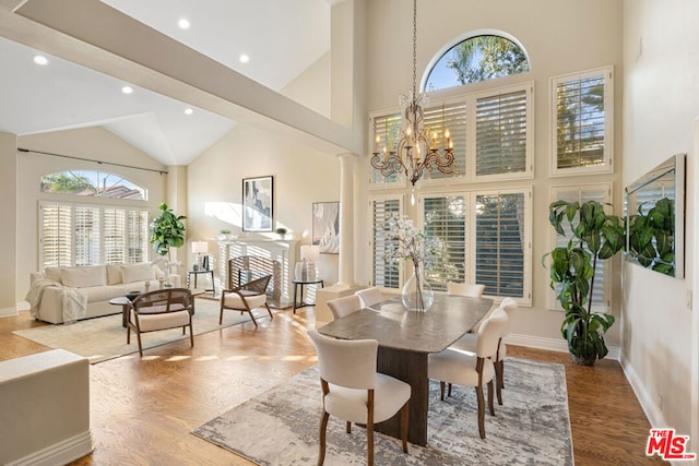 dining room with hardwood / wood-style floors, decorative columns, a chandelier, and high vaulted ceiling