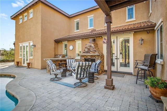 rear view of property with an outdoor stone fireplace, exterior kitchen, a patio, and french doors