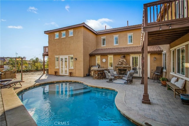 rear view of house featuring an outdoor fireplace and a patio