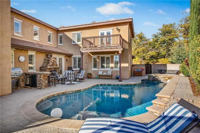 rear view of house with exterior kitchen, a balcony, a fenced in pool, a fireplace, and a patio