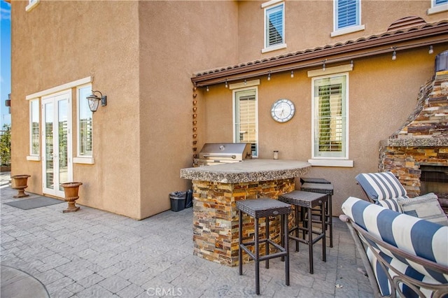 view of patio / terrace featuring a bar, an outdoor kitchen, and a grill