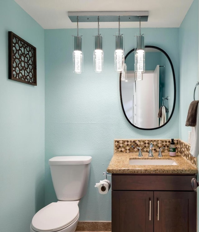 bathroom with toilet, vanity, and backsplash