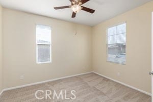 carpeted spare room with a wealth of natural light and ceiling fan