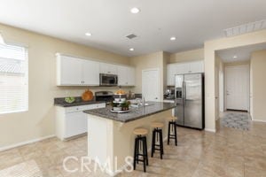 kitchen featuring stainless steel appliances, an island with sink, white cabinets, a breakfast bar, and sink