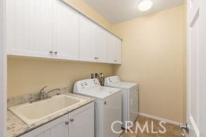 laundry area with washing machine and dryer, sink, and cabinets