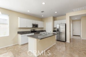 kitchen featuring white cabinetry, stainless steel appliances, a kitchen island with sink, and sink