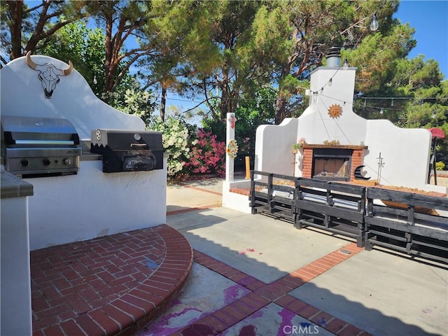 view of patio / terrace featuring an outdoor brick fireplace and a grill