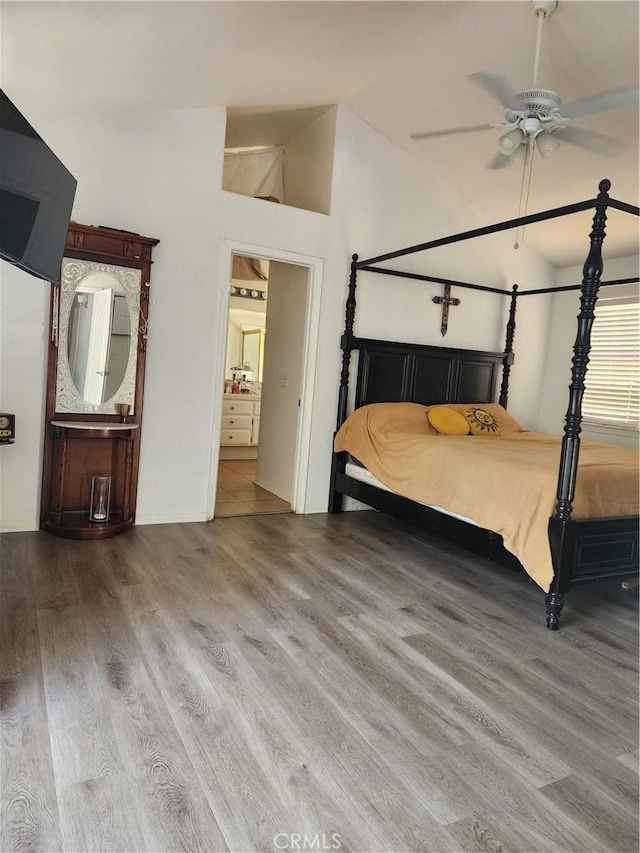 bedroom featuring ceiling fan, ensuite bathroom, lofted ceiling, and wood-type flooring