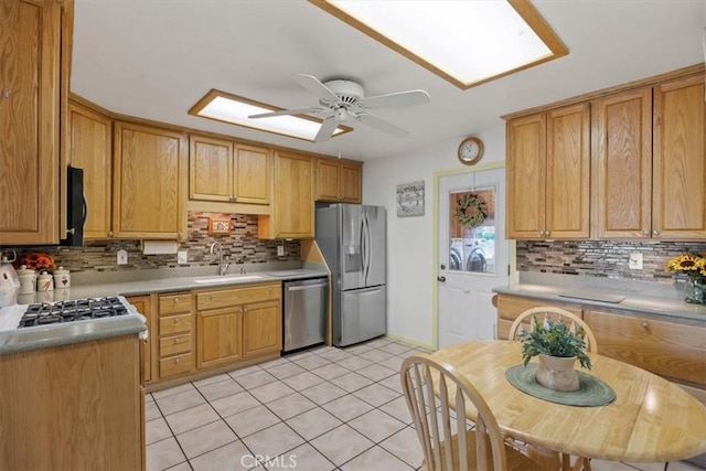 kitchen featuring tasteful backsplash, stainless steel appliances, ceiling fan, sink, and washer and dryer