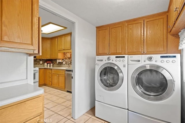 laundry area with washer and dryer, cabinets, light tile patterned floors, and sink