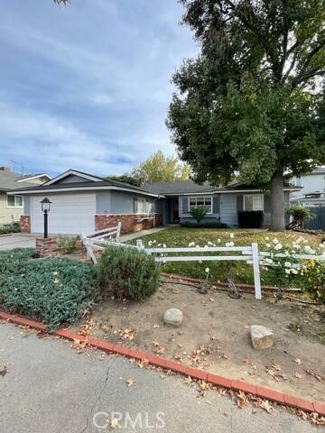 ranch-style home with a garage, driveway, and a fenced front yard