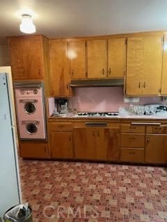 kitchen with cooktop, stacked washer / drying machine, and white refrigerator