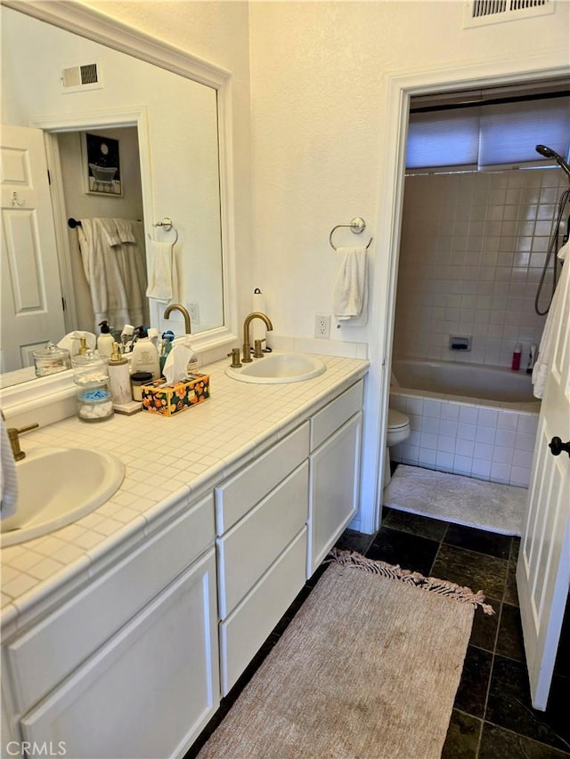 full bathroom with toilet, vanity, and tiled shower / bath