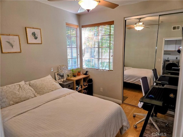 bedroom with hardwood / wood-style floors, ceiling fan, washer / clothes dryer, and a closet