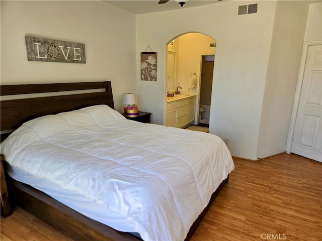 bedroom featuring light wood-type flooring, sink, and ensuite bath