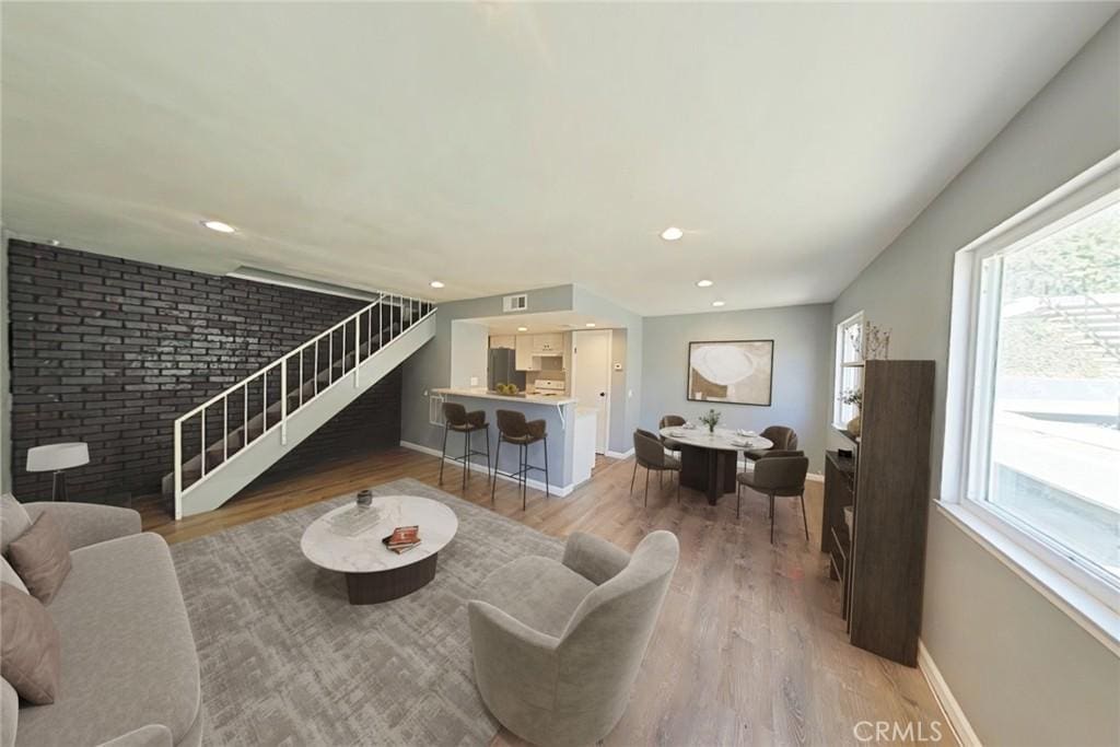 living room with plenty of natural light, wood-type flooring, and brick wall