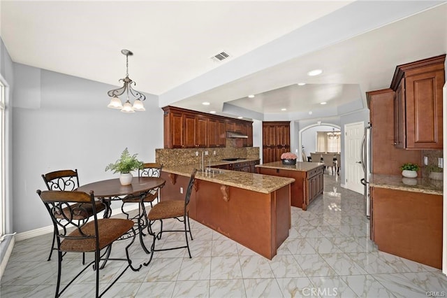 22427 Steeplechase Ln, Diamond Bar, CA 91765 - kitchen featuring arched walkways, under cabinet range hood, a raised ceiling, a peninsula, and recessed lighting