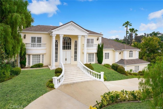 greek revival inspired property featuring a front yard and a balcony