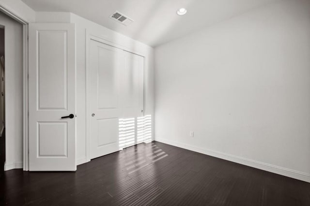 unfurnished bedroom with dark hardwood / wood-style floors and a closet