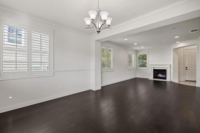 unfurnished living room featuring dark hardwood / wood-style floors, ornamental molding, and a chandelier