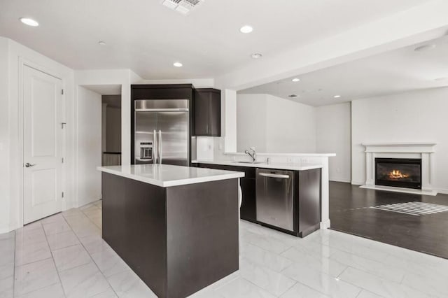 kitchen with kitchen peninsula, sink, a kitchen island, and stainless steel appliances