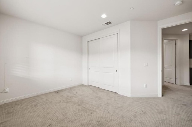 unfurnished bedroom featuring light carpet and a closet