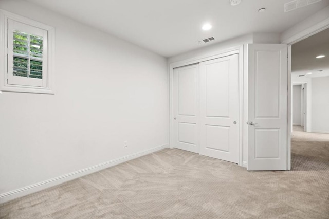 unfurnished bedroom featuring light carpet and a closet