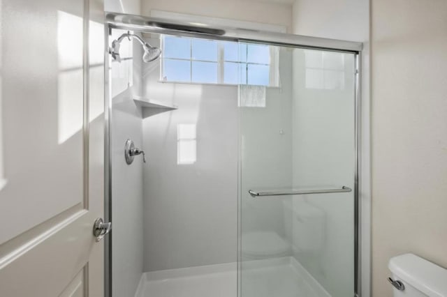 bathroom featuring a shower with shower door and toilet