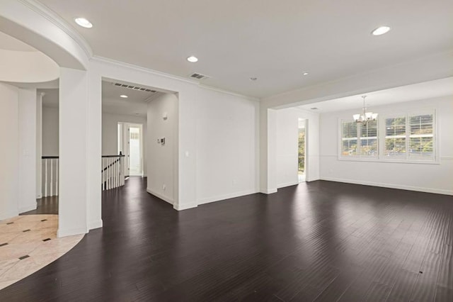 empty room with crown molding, dark hardwood / wood-style flooring, and a notable chandelier