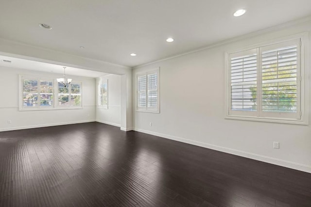 unfurnished room with a wealth of natural light, ornamental molding, dark wood-type flooring, and an inviting chandelier