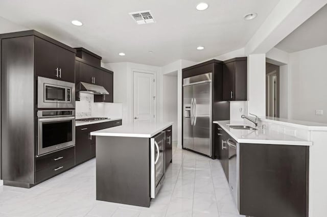 kitchen featuring dark brown cabinetry, sink, wine cooler, built in appliances, and kitchen peninsula