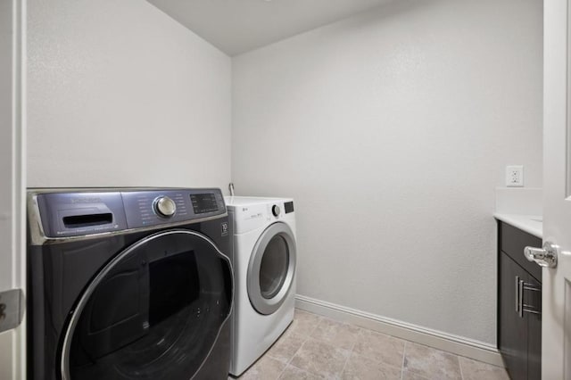 washroom featuring cabinets and washer and clothes dryer