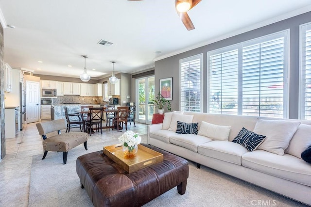 tiled living room with ceiling fan and crown molding