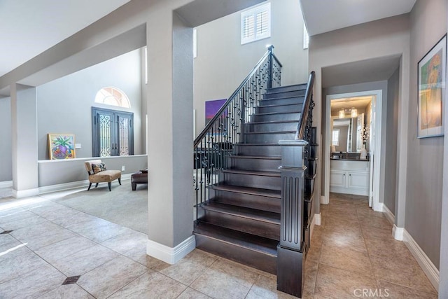 staircase with tile patterned flooring and a high ceiling